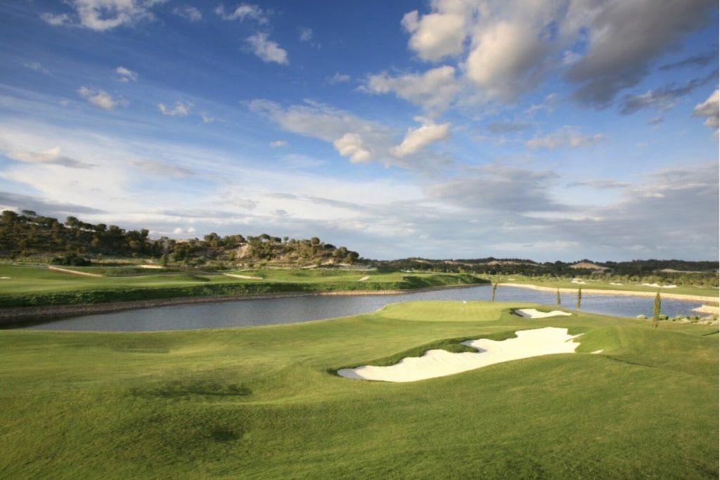 Green and bunkers beside water at Las Colinas Golf and Country Club